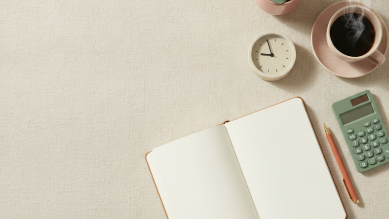 An open notebook, clock, calculator, plant and coffee on linen